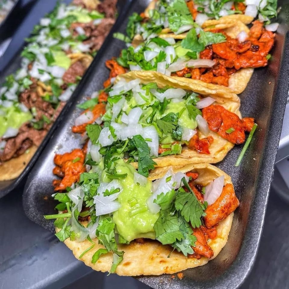 Close-up of Acapela Modern Mex tacos with red meat, guacamole, cilantro, and onions.